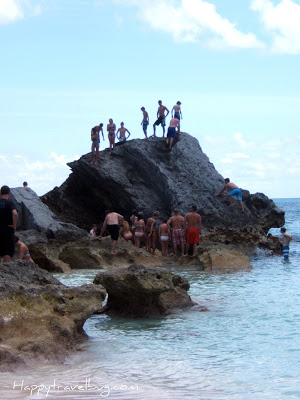 Lots of people climbing on a giant rock in the Bermuda ocean