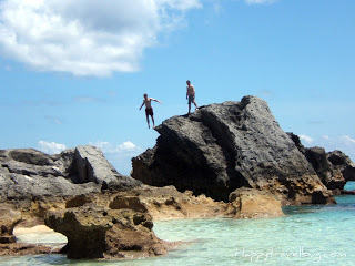 Man jumping off of giant rock in Bermuda ocean