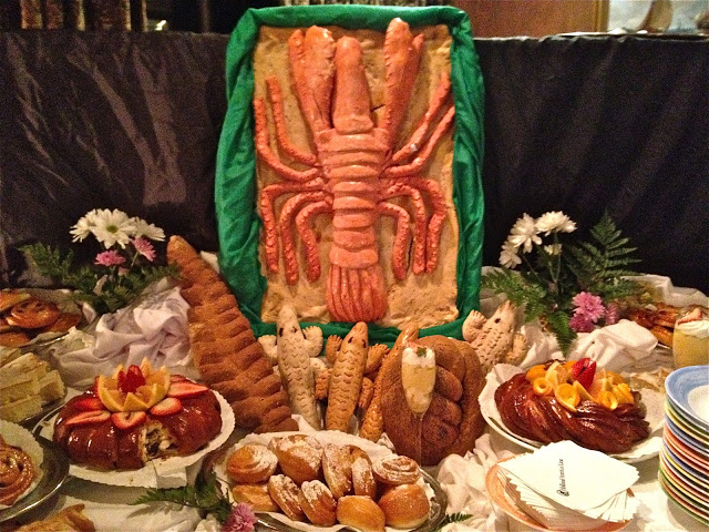 Lobster out of bread surrounded by desserts