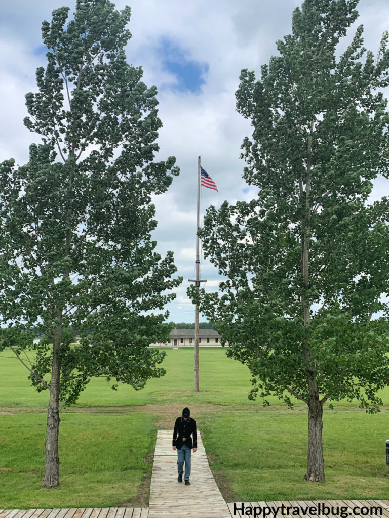 Soldier standing between two large trees with the American Flag in between