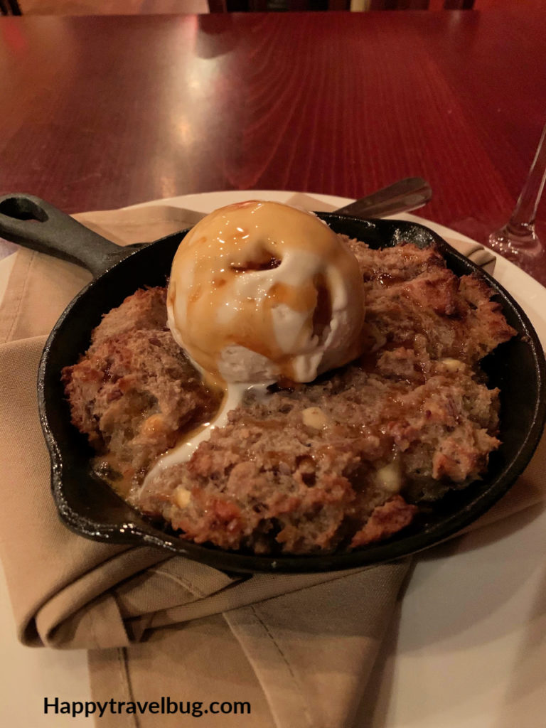 Pumpkin Spice bread pudding in a cast iron skillet with ice cream on top