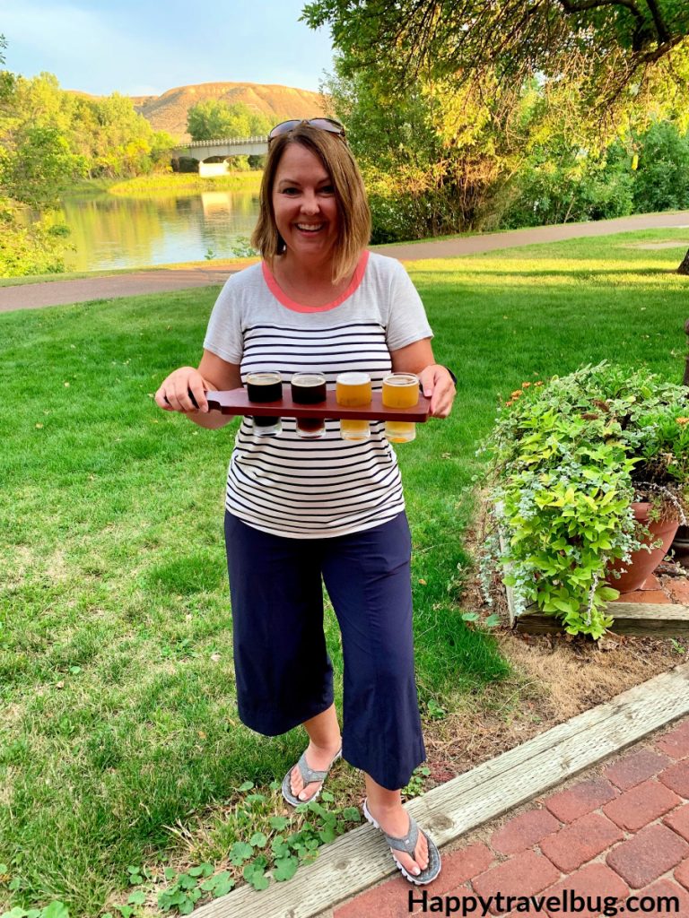 woman with beer samples standing outside by a river