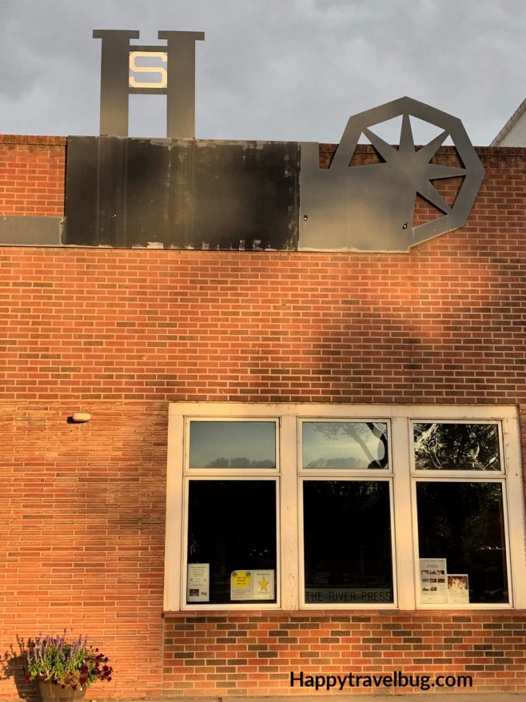 Old brick building with a metal sign of a wheel and the letters SH